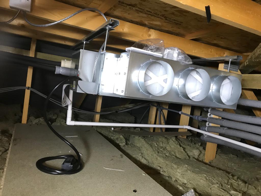 Ducted fan coil unit suspended in a residential loft with condensate drainage