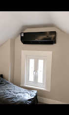Black Daikin wall-mounted air conditioning unit in a bedroom