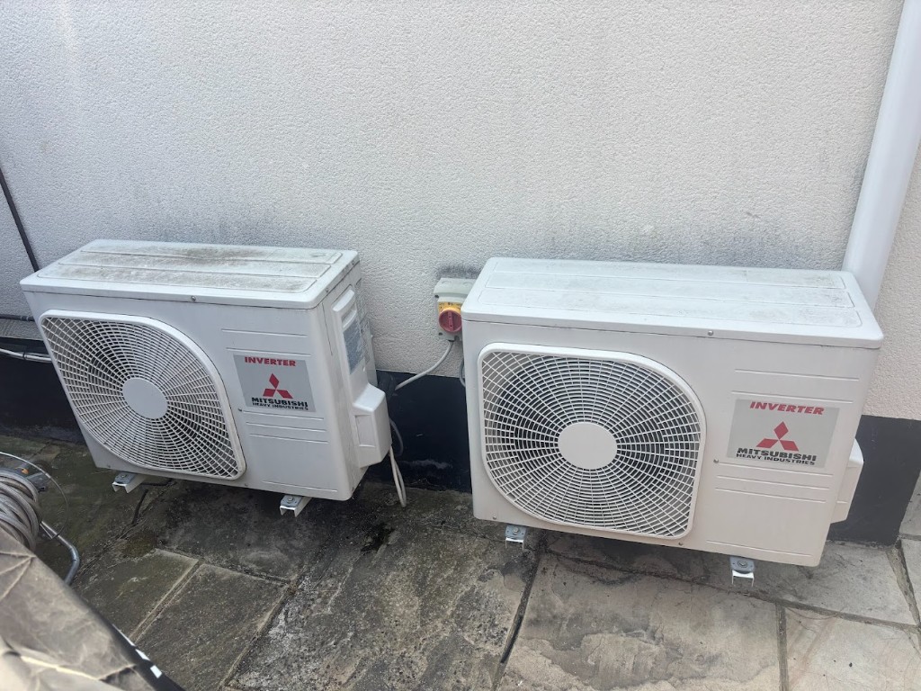 Paired outdoor air conditioning units on stone paving